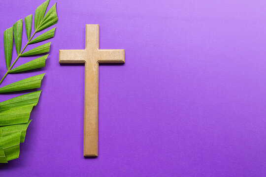 Cross and palm leaves on purple background. Lent season concept.