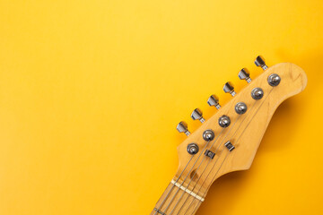 Closeup of electric guitar neck in solid yellow background with copy space - obrazy, fototapety, plakaty