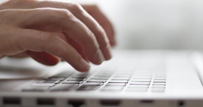 Hands typing on a laptop keyboard, close-up.