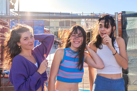 Three friends posing amusingly while eating lillipop outdoors