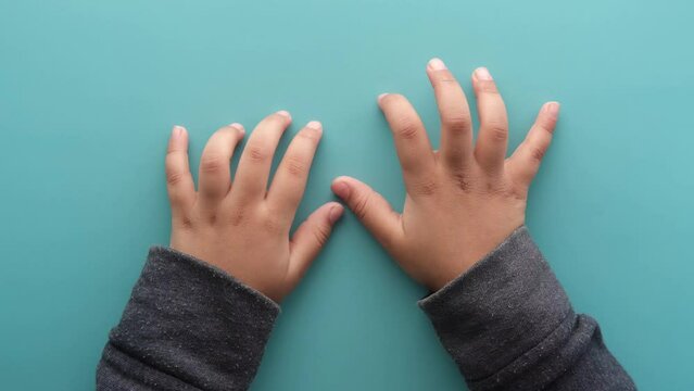 close up of a nervous child hand on light green background 
