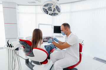 The dentist advises a young beautiful woman about the treatment and prosthetics of teeth in modern...