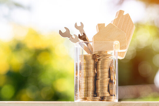 Home models and gold coins and tools, construction equipment and spanners for building or repairing houses put on the wooden table in garden, Loan for restoration real estate or build a house concept.