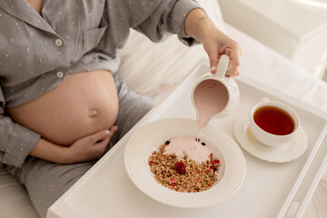 A pregnant girl is having breakfast in bed.