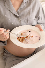 A pregnant girl is having breakfast in bed.