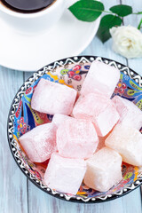 Turkish delight or lokum confection rose and lemon flavored with cup of coffee, vertical, closeup