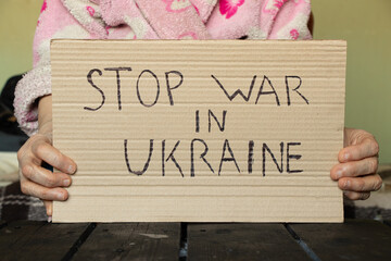 Stop the war in Ukraine written on a sign that a woman holds in her hands from her house in the...