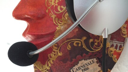 Mund- und Nasenbereich einer Venedig-Maske aus Pappmaché, ein Headset tragend, seitliche Perpektive