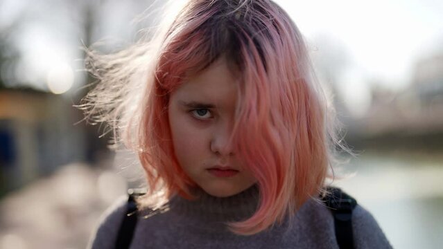 chubby little girl with pink hair on city street, troubled teenager is looking at camera