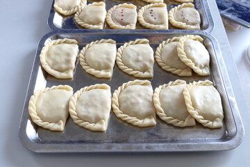Raw curry puffs are on stainless tray before frying in oil, Thailand.