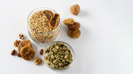 Products for a healthy breakfast, rolled oat groats with dried fruits, nuts and pumpkin seeds on a white background, empty space for text, banner