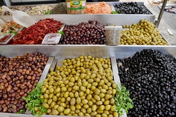 Assortment of black and green olives, dried tomatoes and pickled vegetables at market stand in Sicily, Italy.