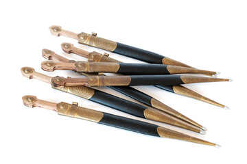 A set of Georgian daggers with metal and leather scabbard on white surface