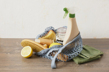 eco cleaning kit in mesh bag on the table, spray bottle, soda, lemon and natural cleaning sponges