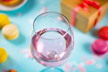 Glass of pink rose wine with donut, macaroons and gift box. Romantic style. Valentines day concept.