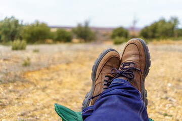Man resting his feet on a footrest in the field in a relaxed way.
