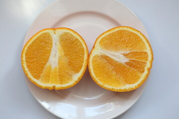 Orange cut in half in a plate on a white background