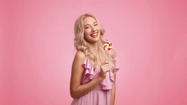 Blonde Lady Eating Lollipop Having Fun Posing Playfully, Pink Background