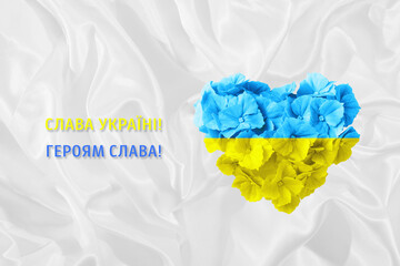 Glory to Ukraine, Glory to the Heroes text in Ukrainian with flower heart in yellow and blue Ukrainian national flag color