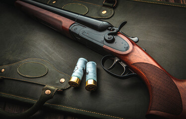 Classic trigger double-barreled hunting rifle on a green background. Smooth-bore hunting rifle open for reloading. Concept postcards for hunters. - obrazy, fototapety, plakaty
