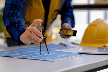 Obraz premium Architects use compasses to draw on building plans for editing, architect engineers design houses and interior structures and draw plans through design programs. Architect concept of building design.