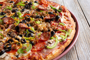 A view of a meat and veggie pizza pie, in a restaurant or kitchen setting.