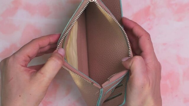 woman opens an empty wallet. there is no money in the wallet.