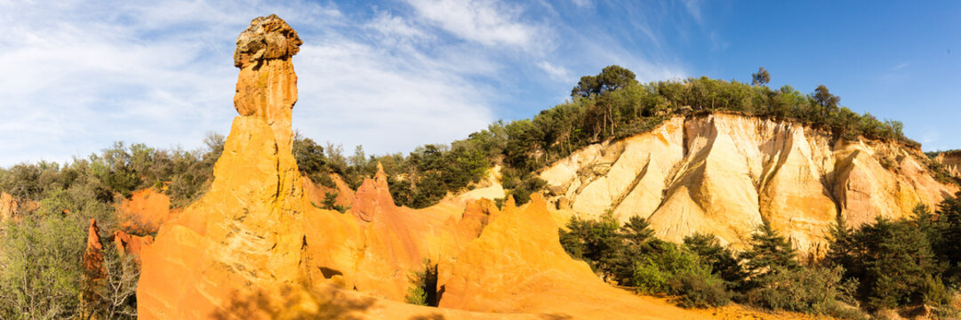Large panorama des ocres de Provence dans le Colorado de Rustrel avec chemin&eacute;e de f&eacute;es et ravinements.