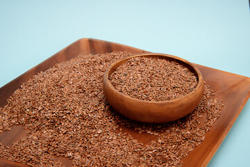 Flax seeds in a wooden bowl on a blue background,healthy food concept