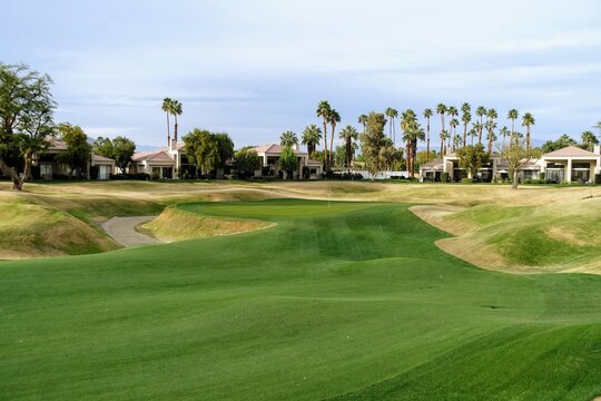 A beautiful photo of a par 4 in perfect condition, from the perspective of the fairway looking towards the green.  The fairway is very undulated.  In Palm Springs, California, United States
