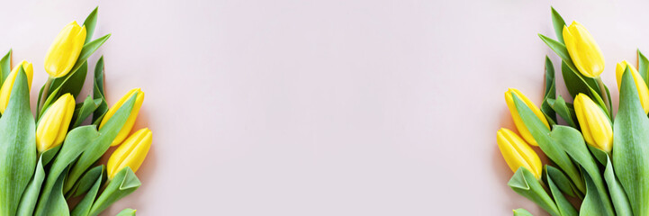 Obraz premium Horizontal web banner with yellow tulips on pink paper with copy space. Background for womens day, 8 March Valentines day, 14 february. Flat lay style, top view, mockup, template, overhead. Greeting