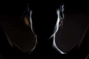 silhouette contour of a beautiful brunette girl. Side lit studio portrait on dark background.