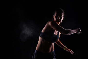 Kickboxer kirl with magnesium powder on her hands, punching with dust visible.