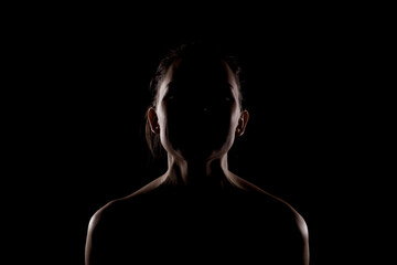 side lit silhouette portrait of a beautiful young woman against dark backgroung