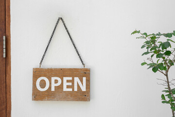 Open sign on wooden planks hanging on the white wall.