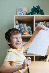 A schoolboy doing math lesson sitting at desk in the children room