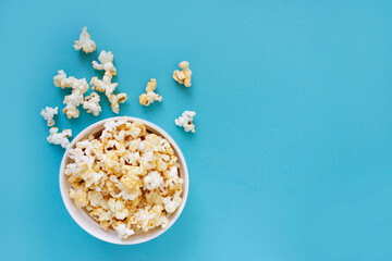 Spilled popcorn on blue background. Movie night concept. Copy space for text