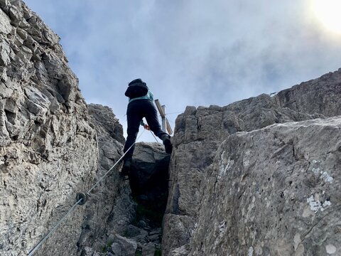 Woman abseiling from peak in Austrian Alps. Vorarlberg, Austria.