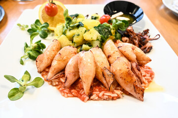 Grilled squid with chard and potatoes served on a plate in a restaurant. Healthy seafood.
