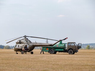 Fuel truck refueling a military helicopter at the airfield