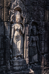 Fototapeta premium Stone bas-relief of ancient Khmer goddess on the temple wall in Angkor complex, Siem Reap, Cambodia