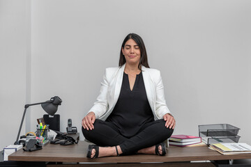 Young business woman meditating on lotus flower, at her desk while taking a break from work. Woman...
