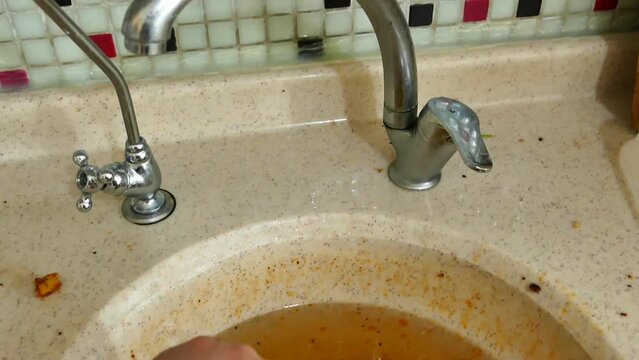 using a plastic kitchen pump to unclog the kitchen sink,a person trying to open the kitchen sink with the sink pump,