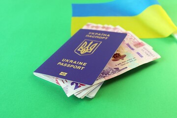 Fototapeta premium Flag of Ukraine, passport and banknotes of the national currency, on a green background, top view, flatly, the concept of travel preparation, tourism, vacation trip
