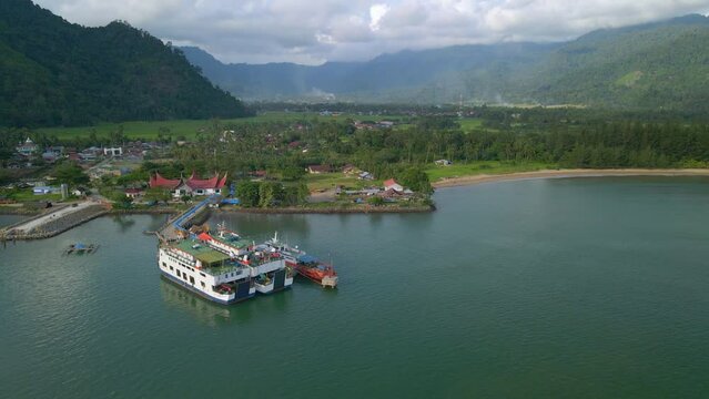 Indonesia, Sumatra Occidental. Wide shot of drone orbiting around tow ferries and one boat at dock in hrabor.