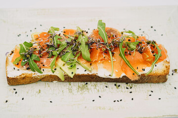 Smoked salmon toast, fresh cheese, avocado and arugula