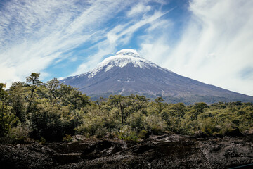 Osorno Volcano seen from the forest in a cloudy day .