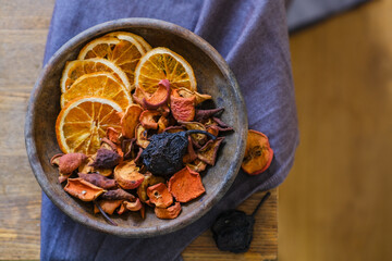 Dried fruits in an old clay plate on a wooden table. Compote. Uzvar. Traditional Ukrainian drink, apple, orange, pear, nutritional supplement, healing, balanced diet, vegan food, vitamins and minerals