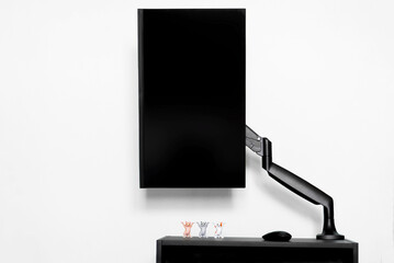 Modern matte computer monitor is installed in a vertical landscape position on a small table using...