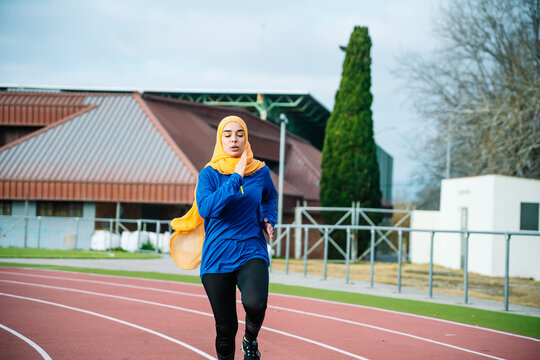 Ethnic Woman In Hijab And Activewear Running On Racetrack